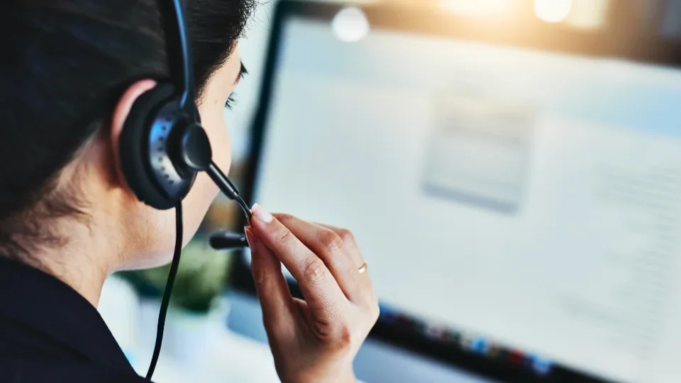 An office worker wearing a headset while looking at a computer screen