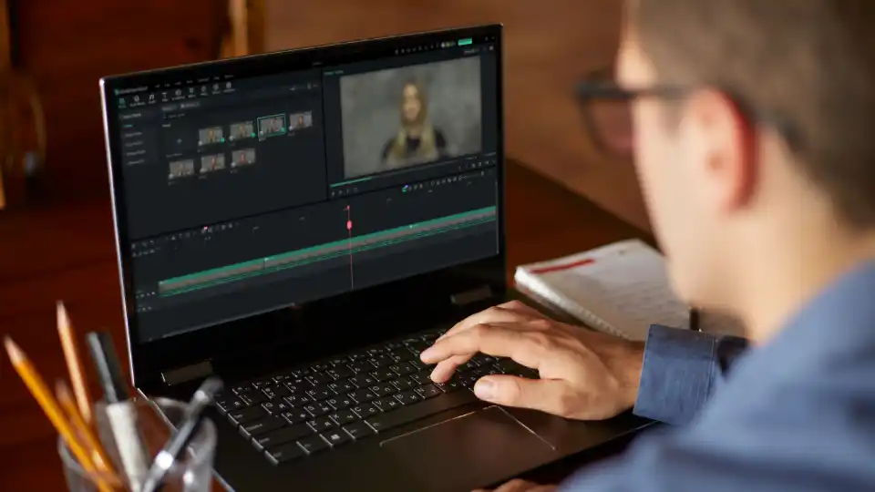 A man editing a video deposition on a laptop.