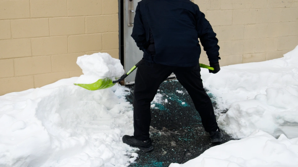 Shoveling Snow An individual shoveling snow outside of a business door.
